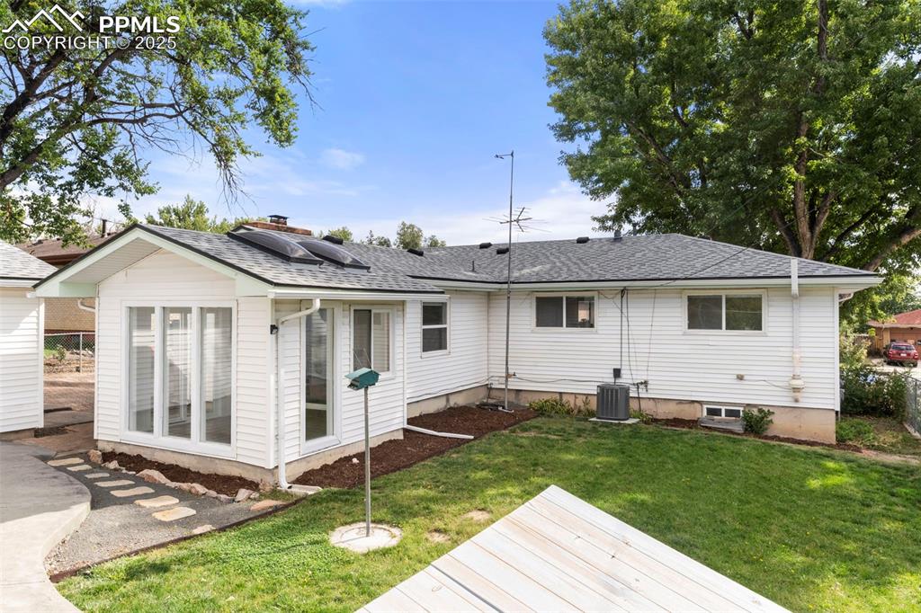 Image 28 of 30: Rear view of house with roof with shingles, a lawn, and roof mounted solar 