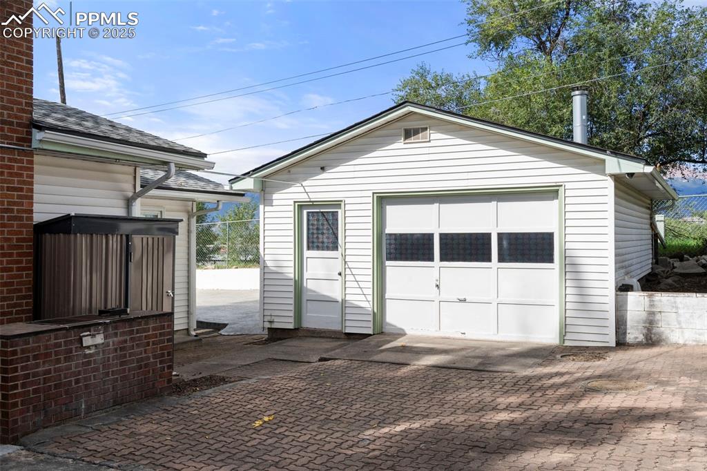 Image 29 of 30: Detached garage featuring decorative driveway