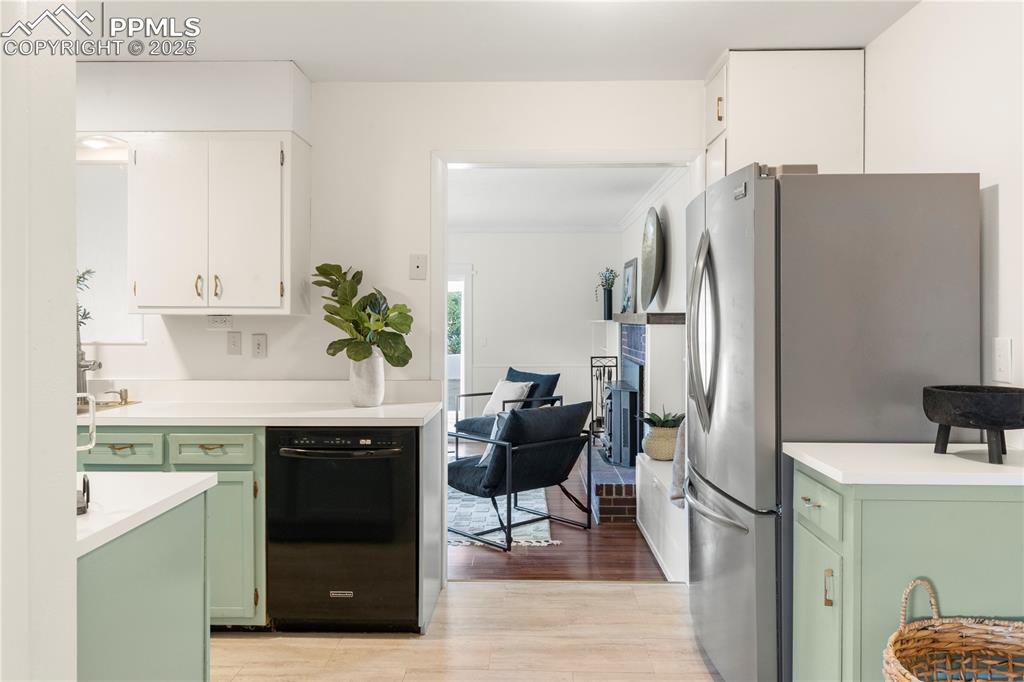 Image 6 of 30: Kitchen featuring green cabinets, freestanding refrigerator, light countert