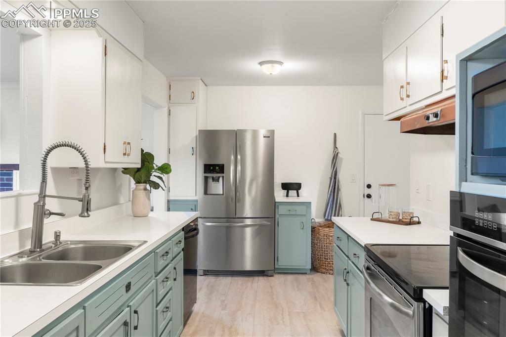 Image 8 of 30: Kitchen featuring stainless steel appliances, light countertops, green cabi