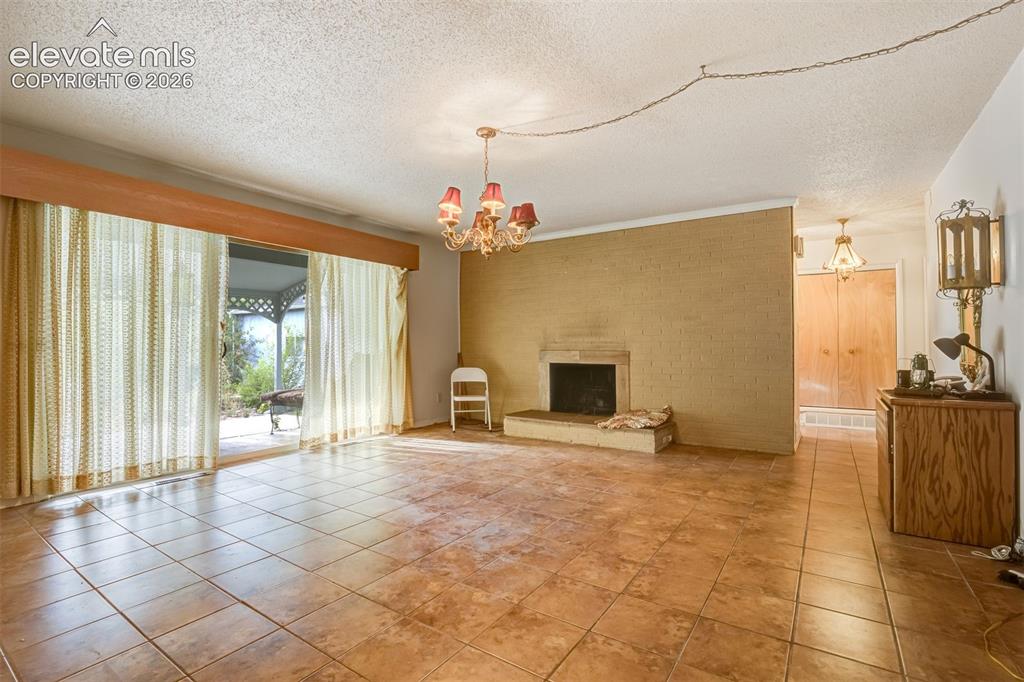 Image 2 of 11: Large living room with fireplace and sliding door accesses the backyard. 