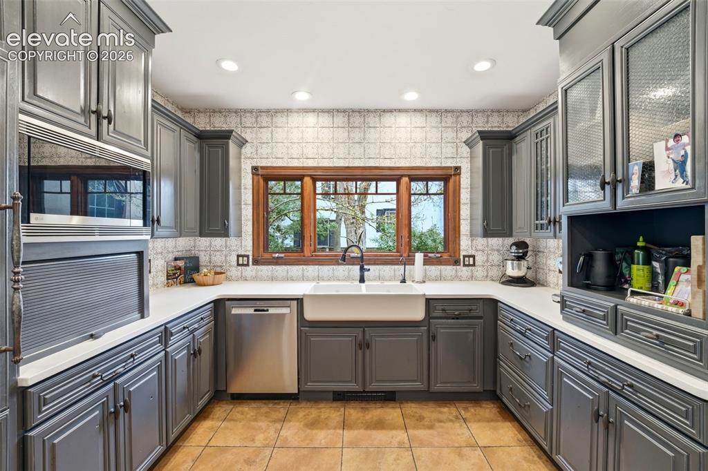 Image 13 of 50: U-shaped kitchen featuring charcoal-painted cabinetry, white countertops, a