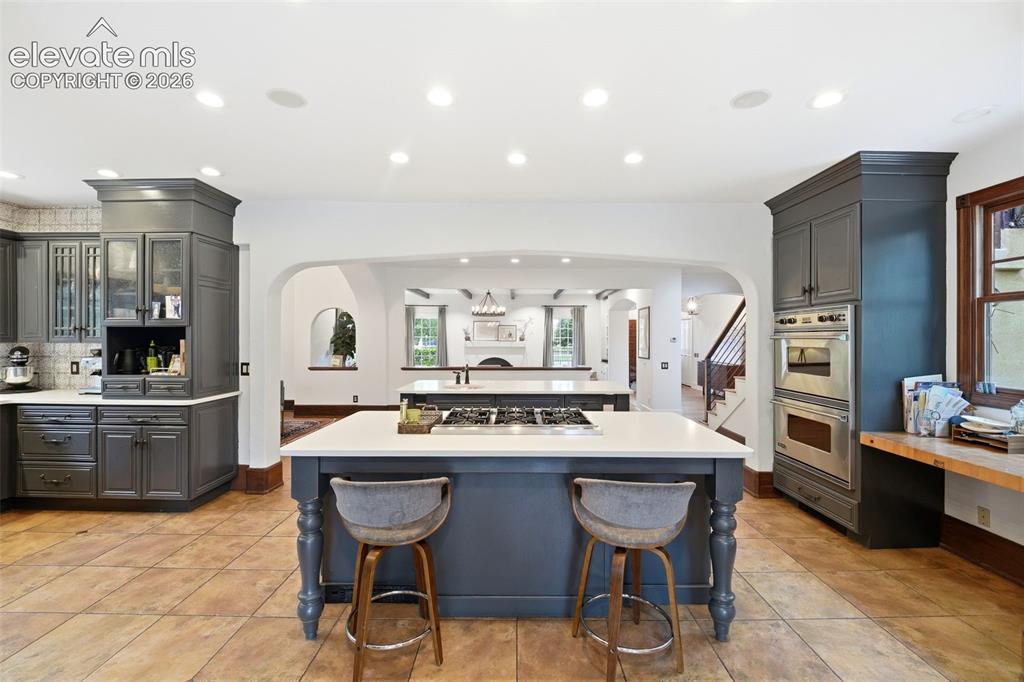 Image 15 of 50: Spacious kitchen featuring an expansive center island with a gas cooktop, s