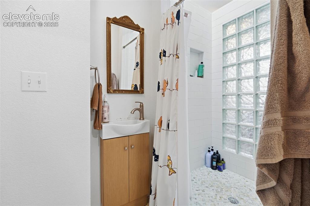 Image 40 of 50: Compact bathroom featuring a glass block shower wall, white subway tile, an