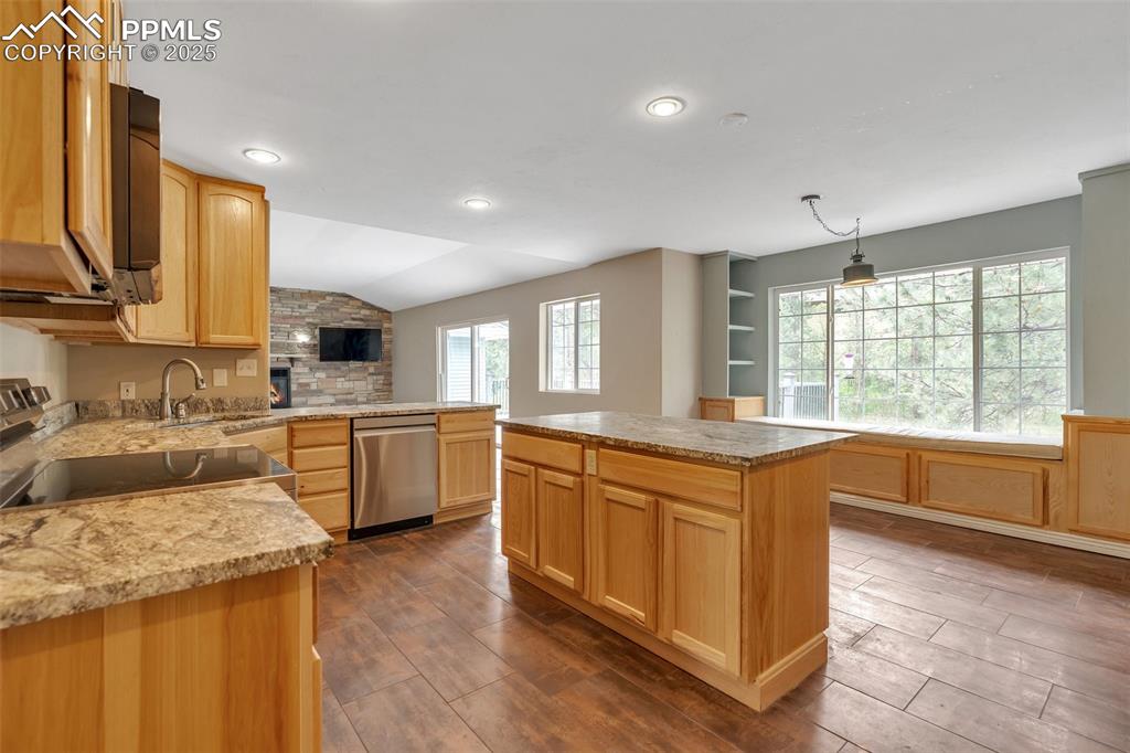 Image 17 of 31: Kitchen with light brown cabinets, vaulted ceiling, appliances with stainle