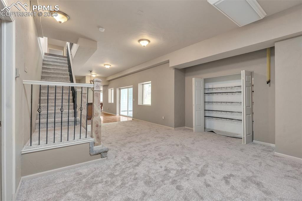 Image 24 of 31: Carpeted empty room with stairs and baseboards