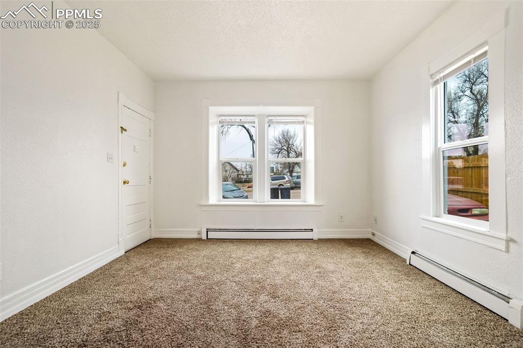 Image 4 of 25: Carpeted empty room with a textured ceiling and baseboard heating