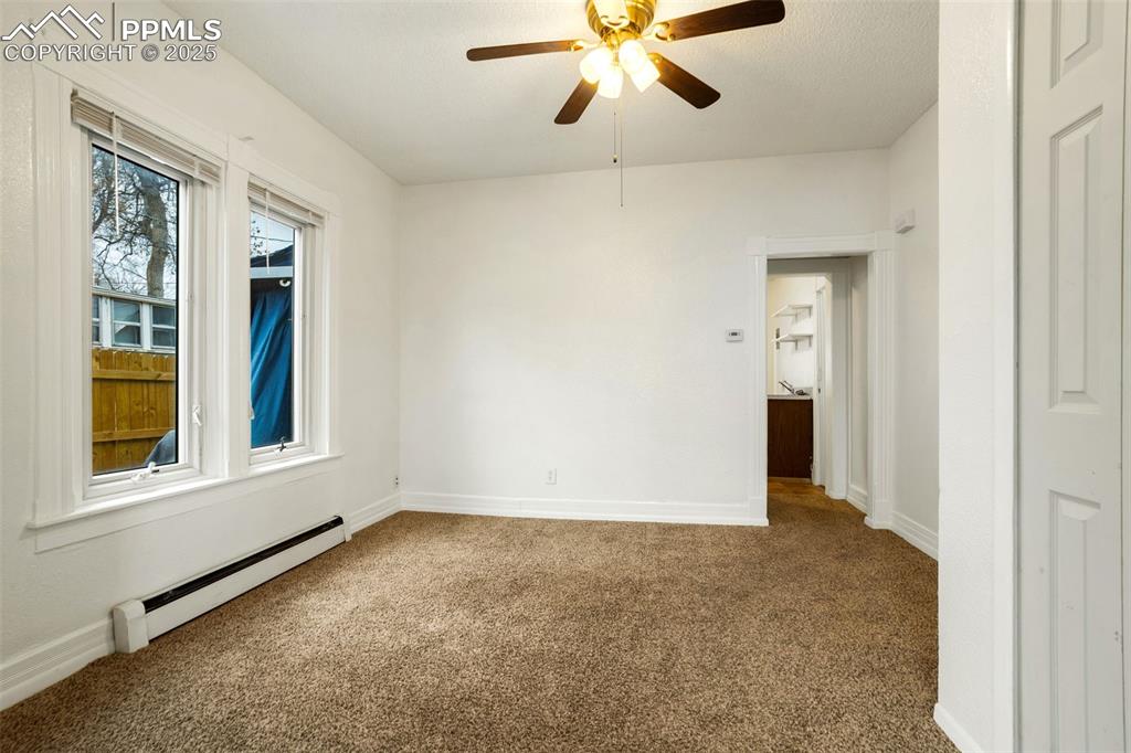 Image 7 of 25: Carpeted empty room with baseboard heating and ceiling fan