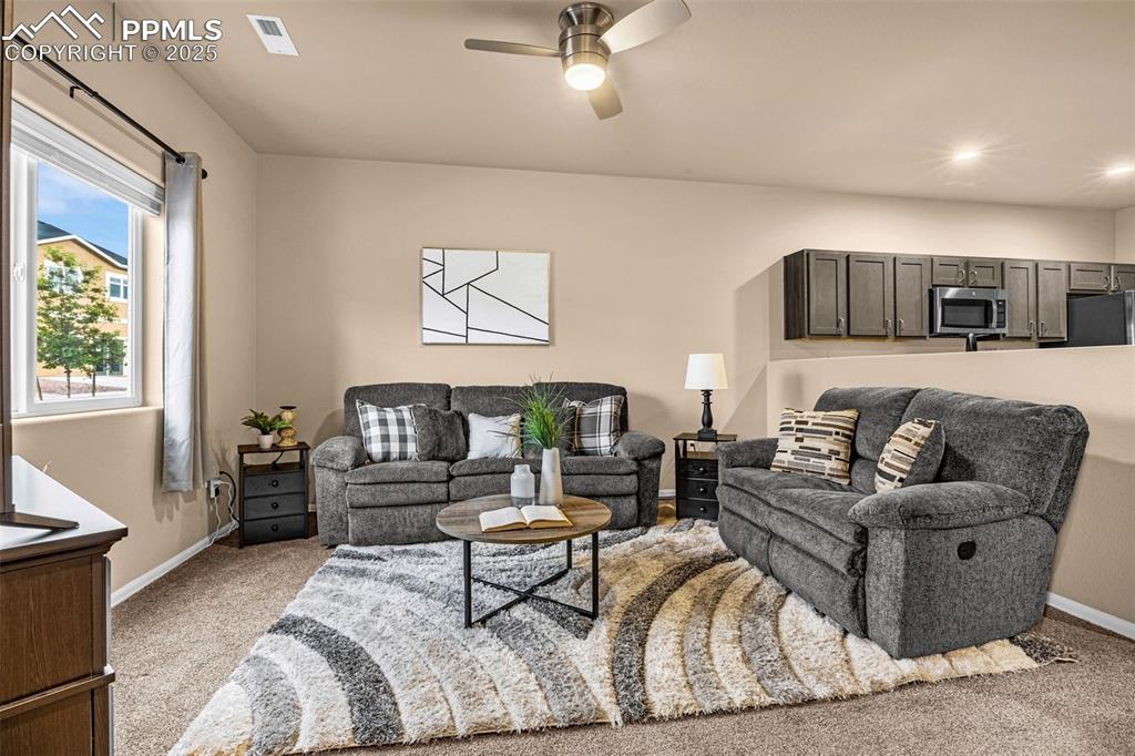 Image 10 of 34: Living room featuring light colored carpet, baseboards, and a ceiling fan