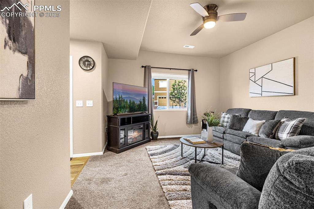 Image 12 of 34: Living area featuring baseboards, carpet floors, ceiling fan, a glass cover