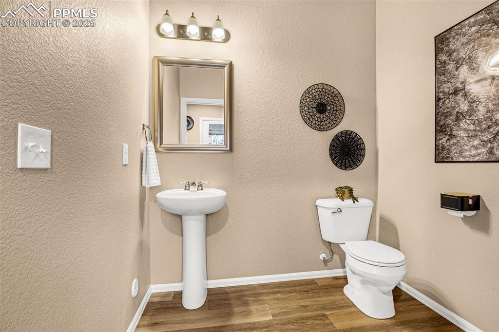 Image 14 of 34: Half bathroom featuring toilet, wood finished floors, a sink, and baseboard
