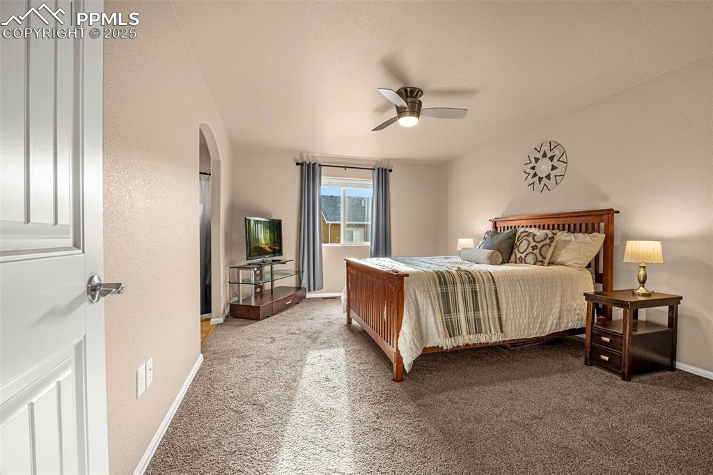 Image 15 of 34: Bedroom with carpet floors, arched walkways, baseboards, and ceiling fan