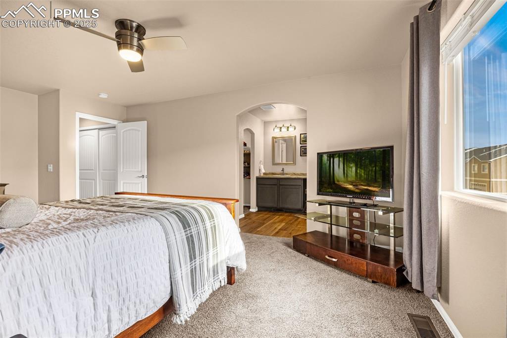 Image 16 of 34: Carpeted bedroom with arched walkways, baseboards, ensuite bath, a closet,