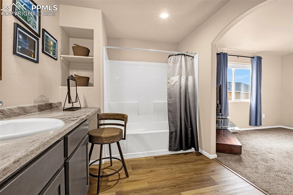 Image 18 of 34: Bathroom featuring shower / bathtub combination with curtain, vanity, wood