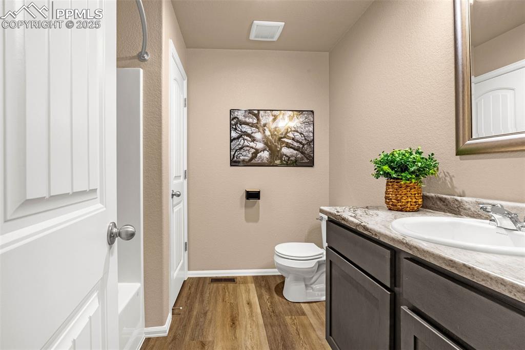 Image 20 of 34: Bathroom featuring wood finished floors, vanity, toilet, and baseboards