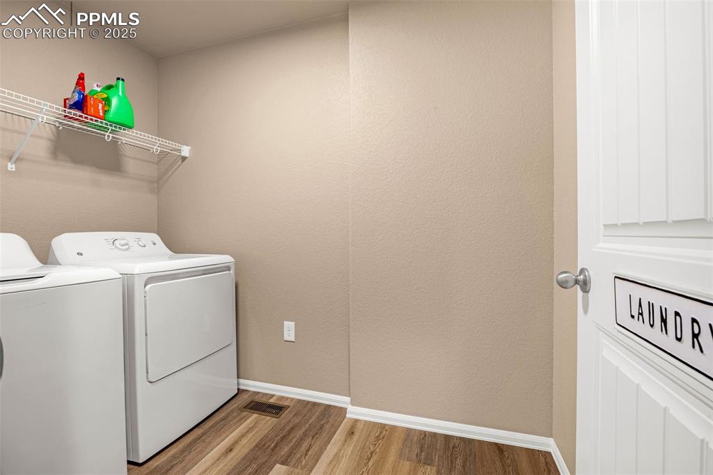 Image 21 of 34: Laundry area with separate washer and dryer, wood finished floors, and base