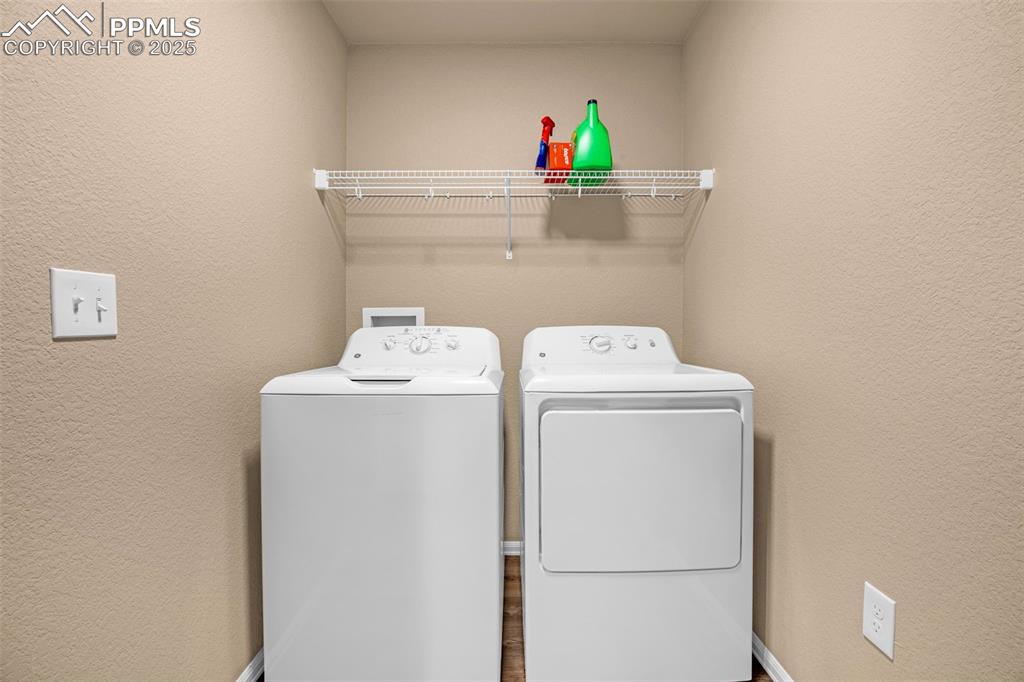 Image 22 of 34: Laundry area featuring washing machine and clothes dryer and a textured wal