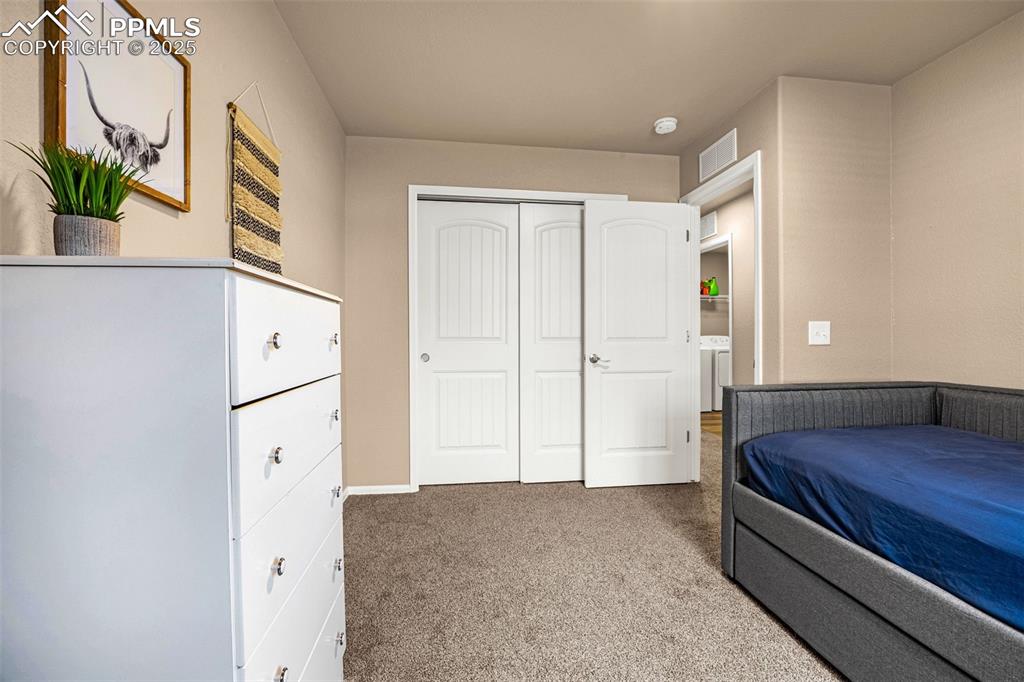Image 25 of 34: Carpeted bedroom featuring washer / dryer and a closet