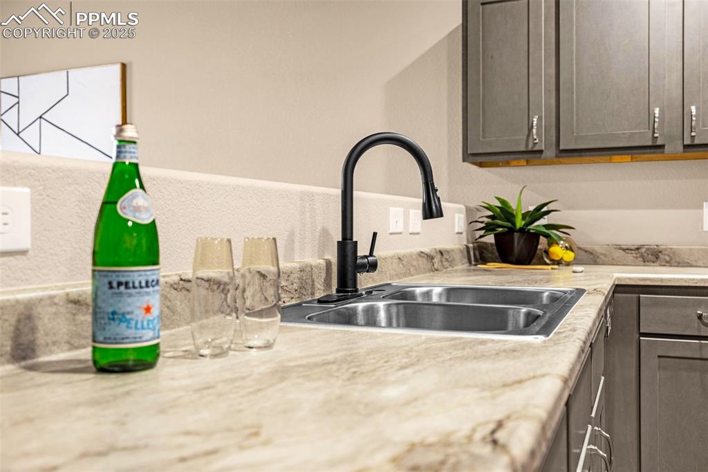 Image 6 of 34: Kitchen view of a sink, light countertops, and gray cabinetry