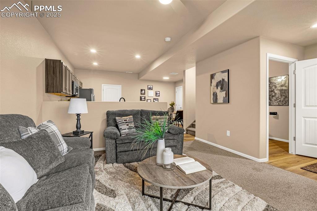 Image 9 of 34: Living area featuring stairway, light colored carpet, baseboards, and reces