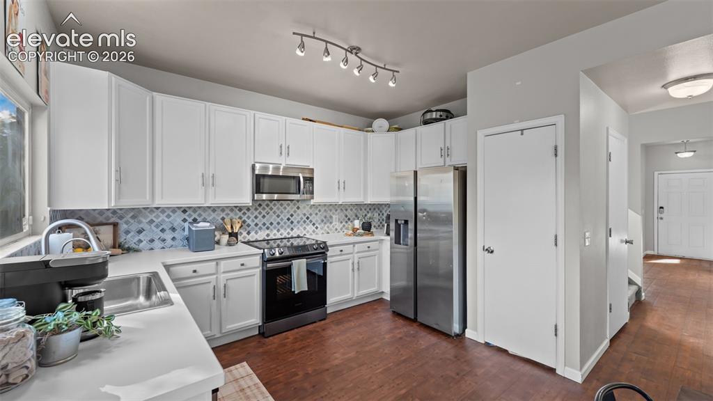 Image 11 of 26: Contemporary kitchen featuring white cabinetry, light-toned countertops, st