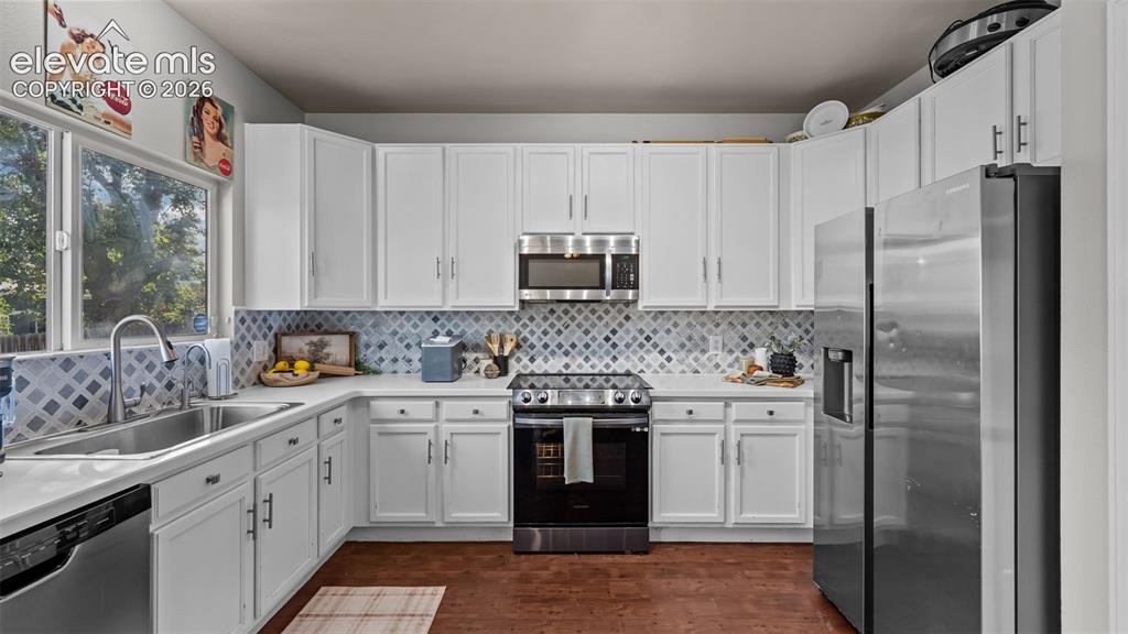 Image 13 of 26: White cabinetry with matte black hardware, stainless steel appliances, patt