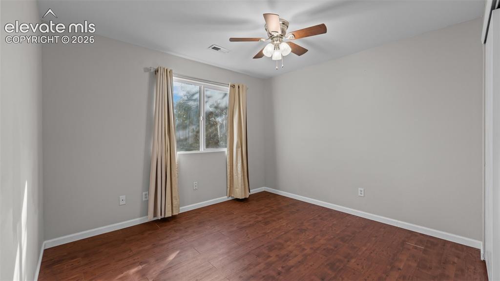 Image 16 of 26: Wood-finish flooring, a ceiling fan with integrated lighting, and a window