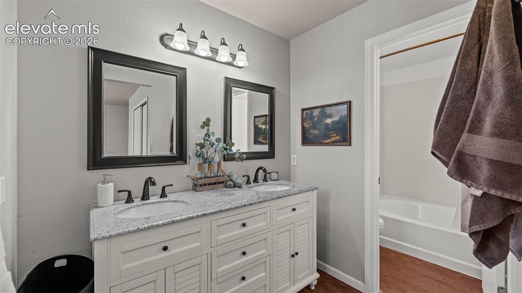 Image 19 of 26: Dual vanity with granite countertop, undermount sinks, and black-finish har