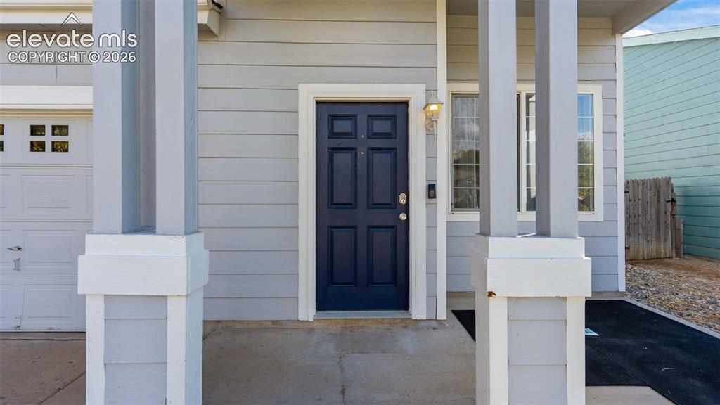 Image 4 of 26: Siding exterior with a paneled front door, an exterior light fixture, and w