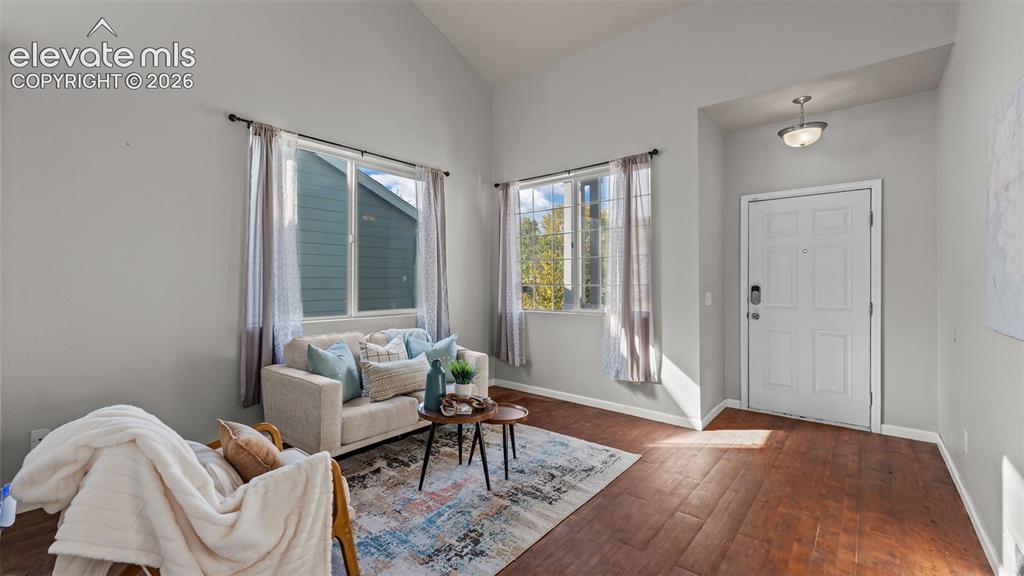 Image 6 of 26: Vaulted ceiling, wood-finish flooring, white paneled entry door, and a flus