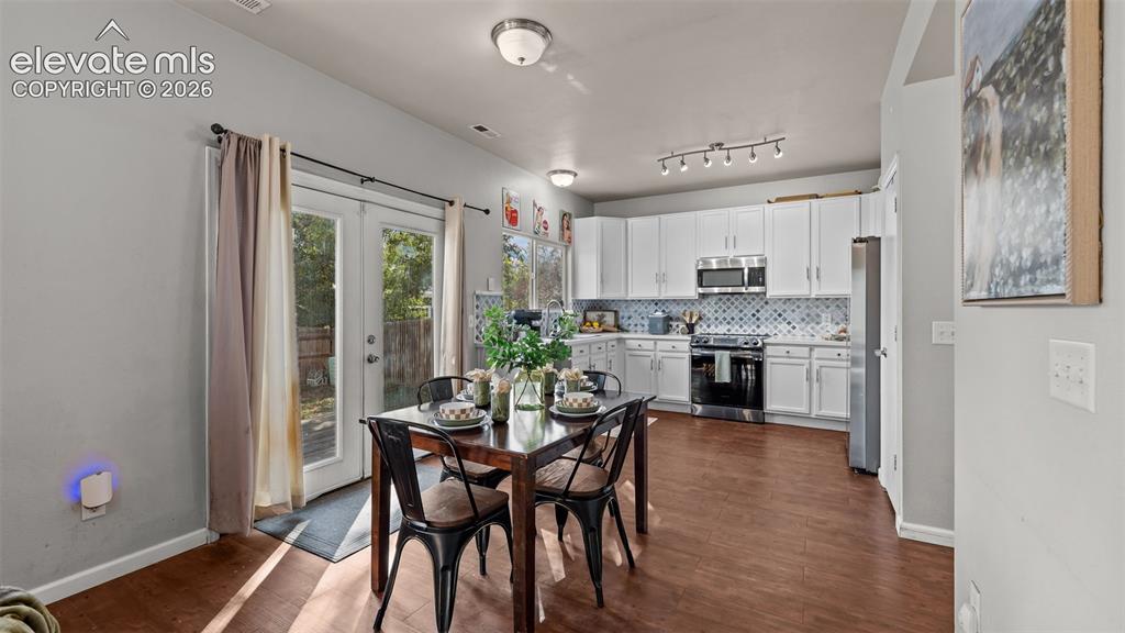 Image 8 of 26: Open-concept kitchen with white cabinetry, stainless steel appliances, and 