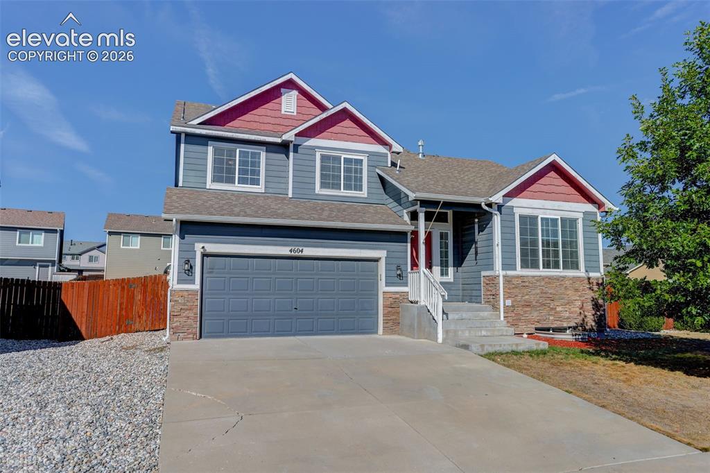 Caption: Exterior featuring a two-car garage, stone accent siding, a covered entry, and a concrete driveway