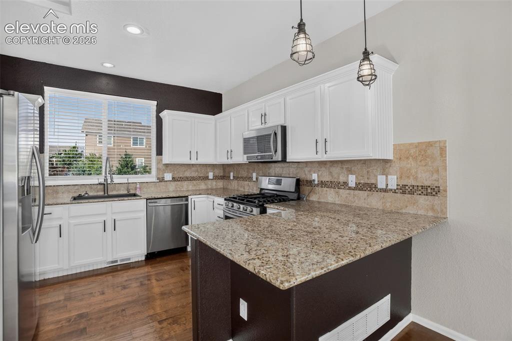 Image 12 of 46: Kitchen featuring white cabinetry, stainless steel appliances, granite coun