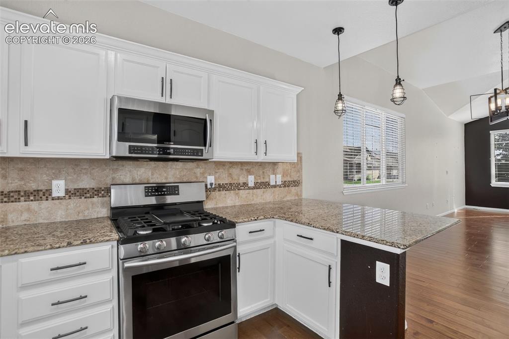 Image 13 of 46: White cabinetry, stainless steel appliances, granite countertops, tile back