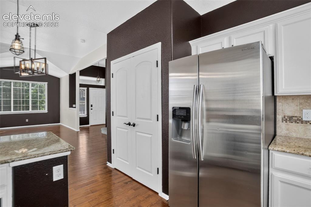 Image 15 of 46: Stainless steel refrigerator, white cabinetry, light granite-style countert