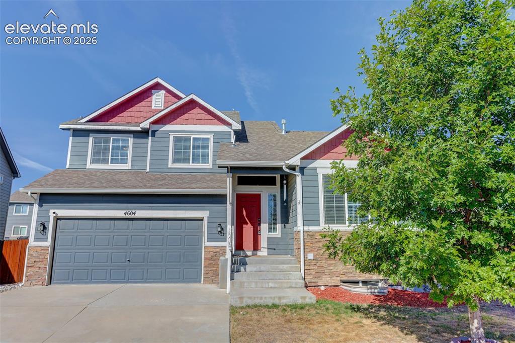 Image 2 of 46: Two-story residence featuring composite siding, stone veneer accents, and a