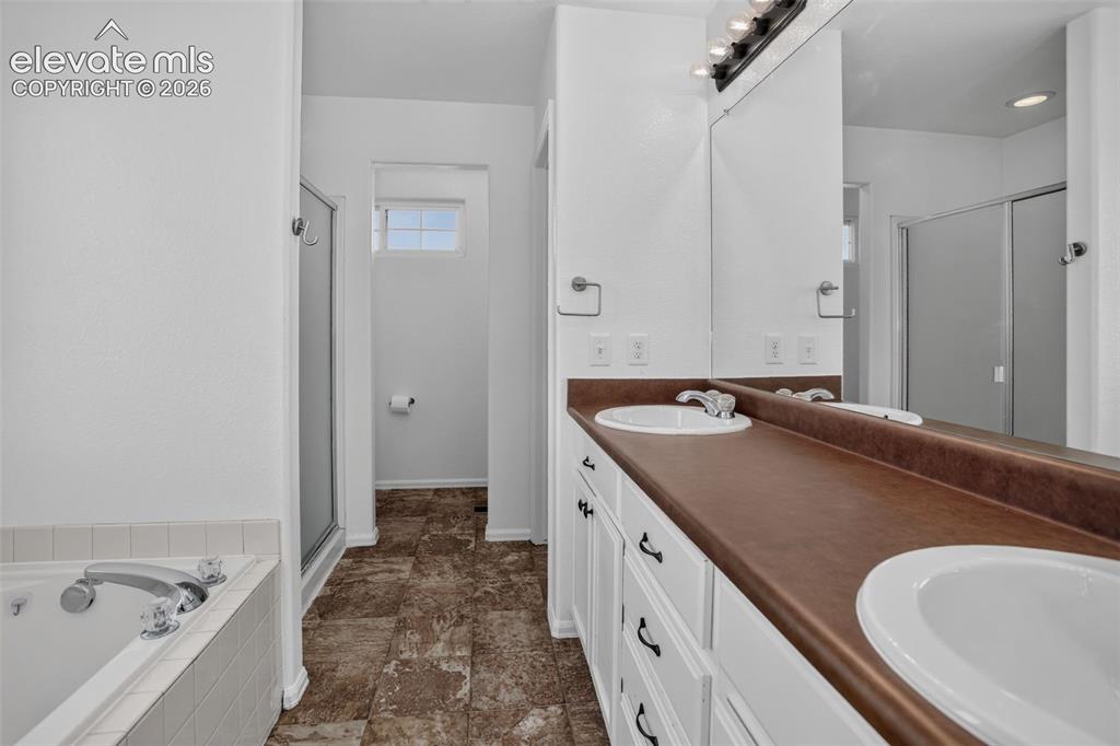 Image 20 of 46: Dual basin vanity with white cabinetry, integrated mirror, large soaking tu