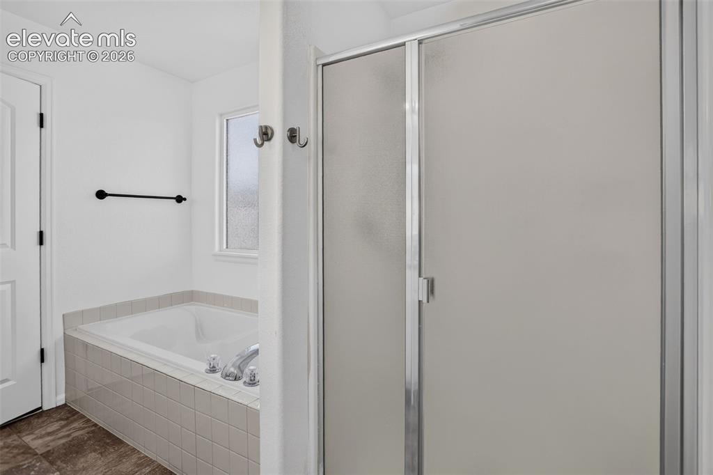 Image 21 of 46: Built-in soaking tub with tile surround, frosted glass shower enclosure, an