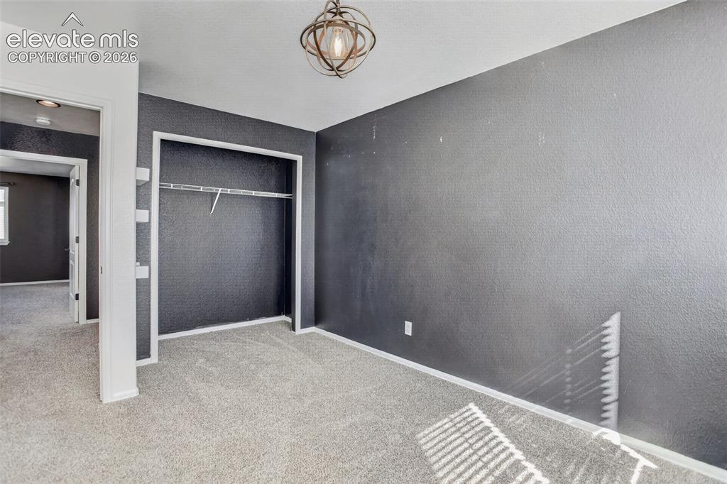 Image 26 of 46: Carpet flooring, textured walls, built-in closet with shelving and hanging 