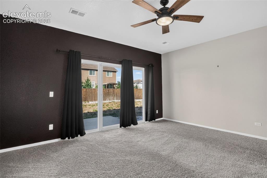 Image 31 of 46: Sliding glass doors, wood-finish ceiling fan with lighting, and plush carpe
