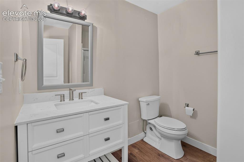 Image 37 of 46: White vanity with integrated sink, brushed nickel faucet, framed mirror, an