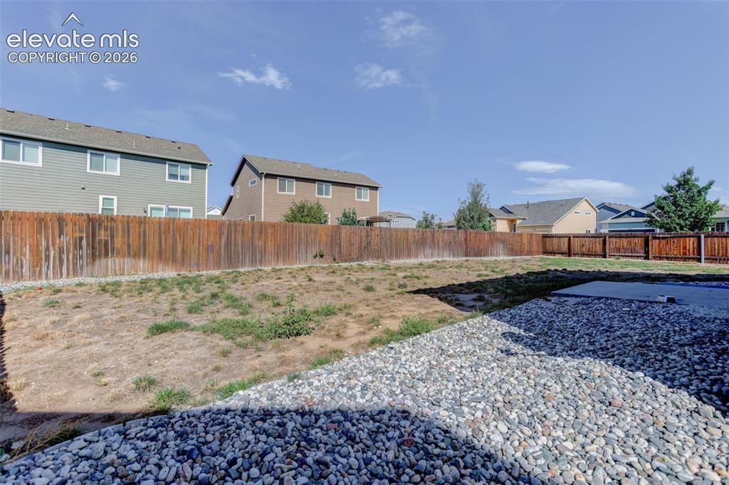Image 40 of 46: Expansive outdoor space featuring a wood fence, gravel landscaping, and a c