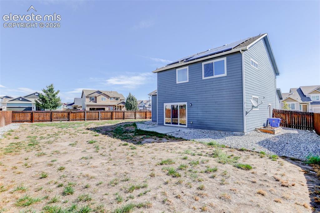 Image 43 of 46: Expansive backyard with a full perimeter wood fence, a gravel border, and a
