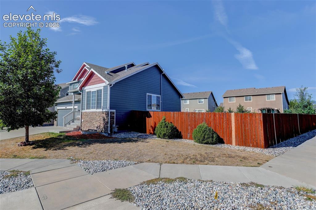 Image 46 of 46: Siding exterior with stone accents, fenced perimeter, and established lands
