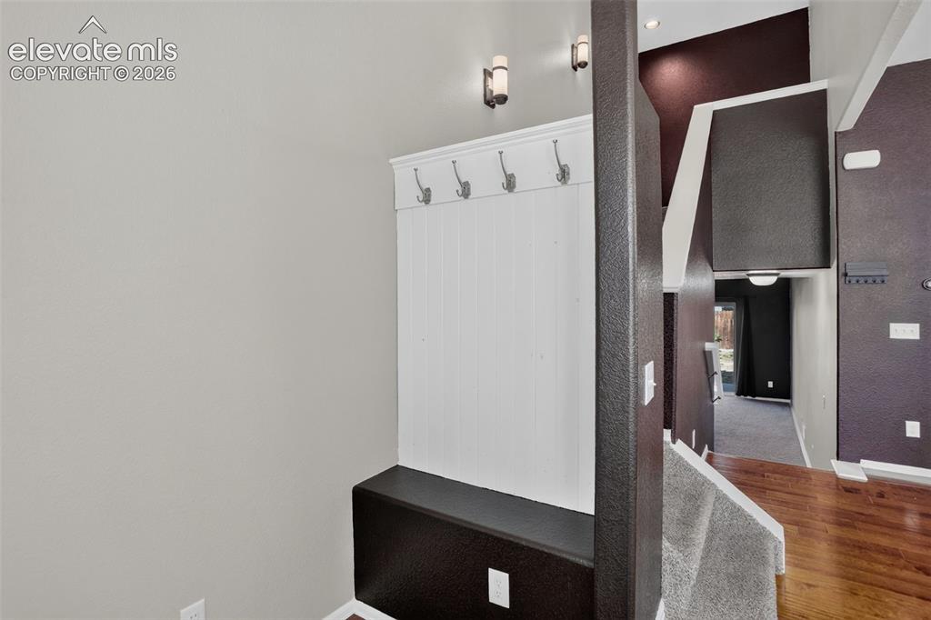 Image 7 of 46: Built-in bench with coat hooks, accent wall finishes, and recessed lighting