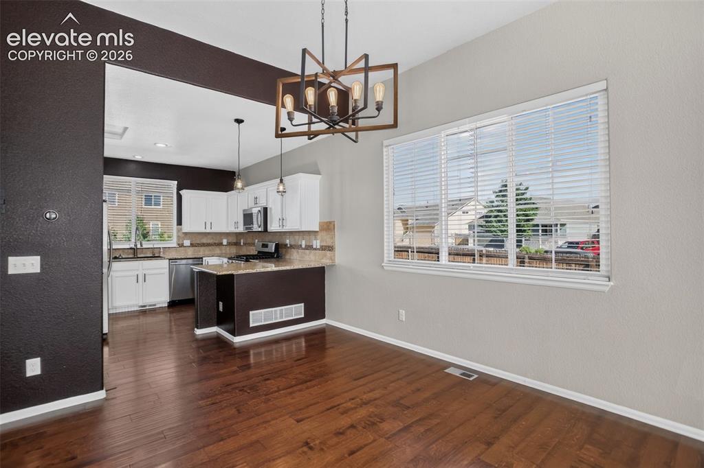 Image 9 of 46: Wood-finish flooring throughout, framed window with blinds, and a kitchen f