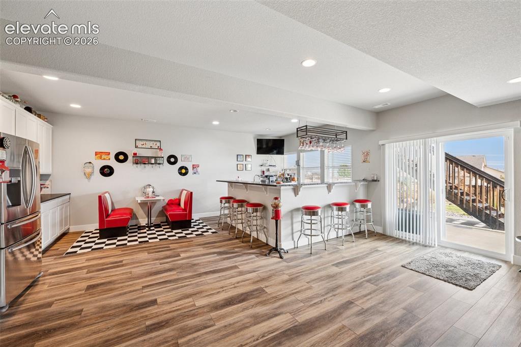 Image 31 of 40: Basement kitchen/wet bar featuring stainless steel refrigerator and cute an