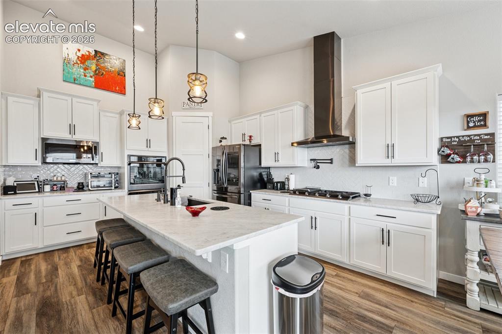 Image 8 of 40: Large gourmet kitchen showcasing beautiful white cabinetry, a breakfast bar