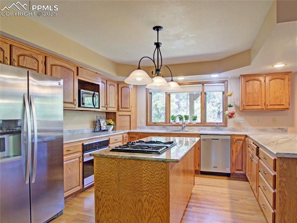 Image 12 of 40: Kitchen has stainless steel appliances, island with granite and gas burner 
