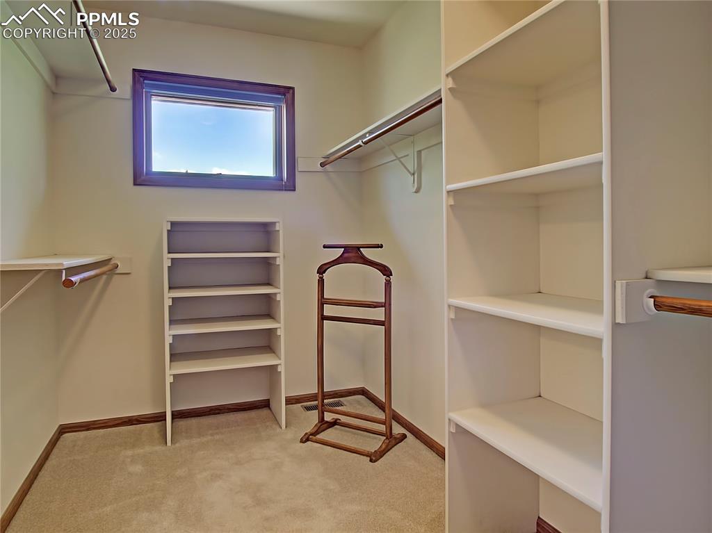 Image 27 of 40: Master walk-in closet has plenty of hanging space and built-in shelves on b